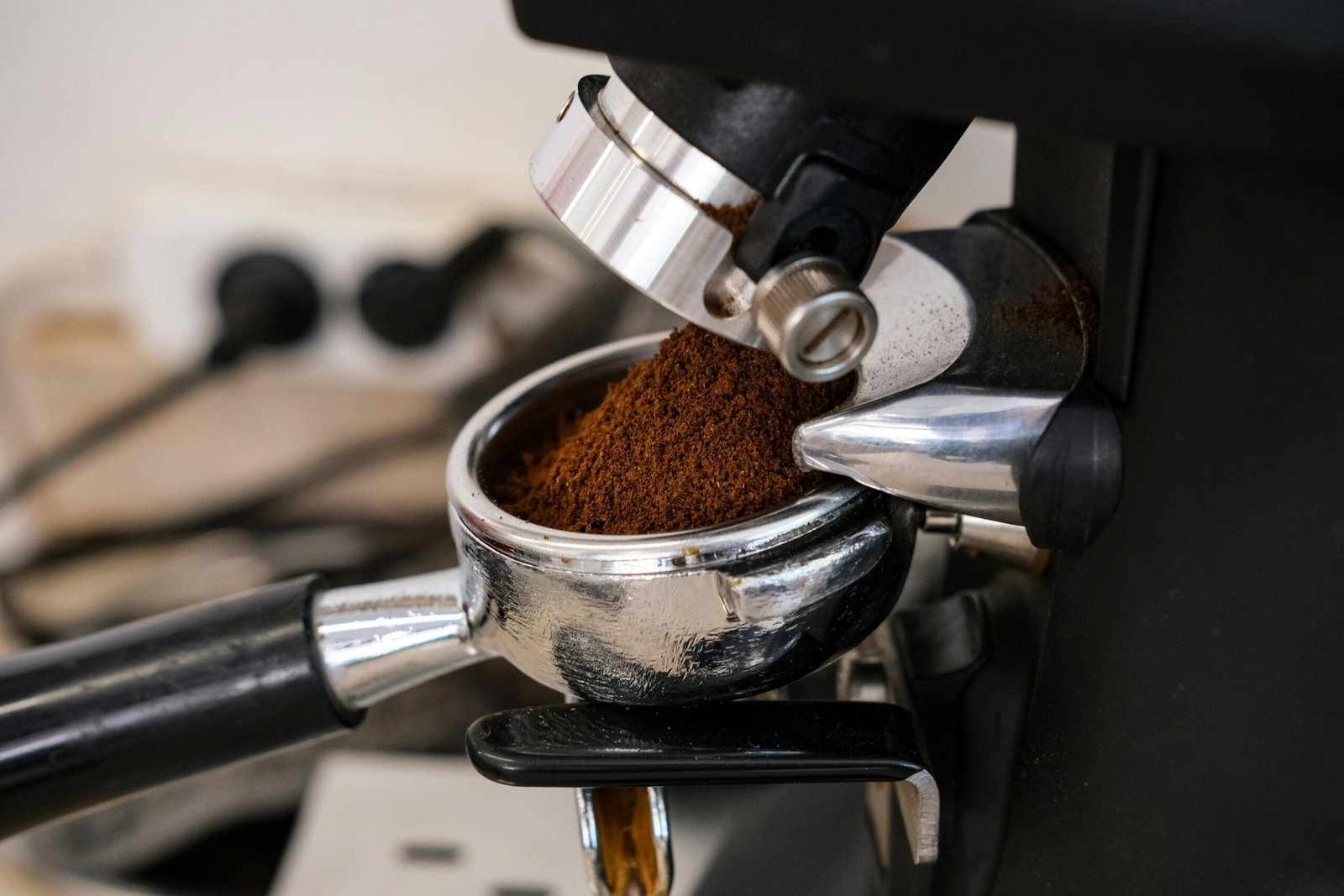 Detailed shot of an espresso machine dispensing fresh coffee grounds into a portafilter.